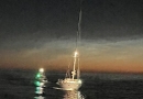 Die manövrierunfähige Segelyacht im Schlepp der HAMBURG, dahinter das Tochterboot ST. PAULI. Am Horizont ist das erste Licht des Tages zu sehen.
